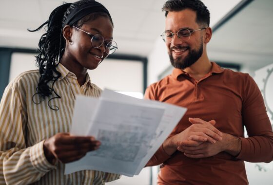 Smiling colleagues discussing documents in modern office